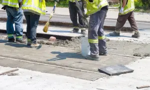 Prace interwencyjne: robotnicy w kamizelkach odblaskowych wylewają beton na torowisko.