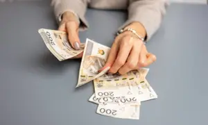 Dłonie liczą banknoty 200 zł, przygotowując świadczenie urlopowe.