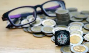 Okulary i kompas na stosie monet. Czy to symbol dofinansowania do okularów, które pomoże Ci odnaleźć drogę do lepszego widzenia?