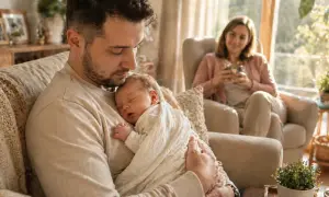 Ojciec tuli śpiące dziecko, a matka patrzy z uśmiechem. Czas na urlop ojcowski, ile płatny?