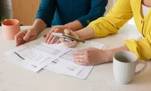 Dwie kobiety analizują dokumenty, być może dotyczące pełnomocnictwa szczególnego. Na stole stoją kubki.