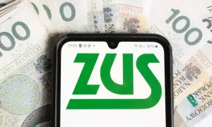 ZUS na ekranie telefonu na tle banknotów 100 zł. Sprawdź aktualną stopę procentową składek na ubezpieczenie wypadkowe.