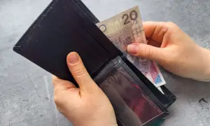 Ręce wkładają banknot 20 zł do portfela. Zastanawiasz się, po jakim czasie od zarejestrowania wypłacany jest zasiłek dla bezrobotnych?