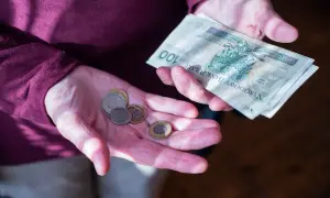Dłonie pokazują monety i banknot 100 zł. Zastanawiasz się, ile wynosi dodatek do emerytury za warunki szkodliwe?