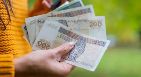 Ręka trzyma polskie banknoty 200 zł. Dowiedz się, jak obliczyć ekwiwalent za urlop, by mieć pewność, że otrzymasz należne pieniądze.