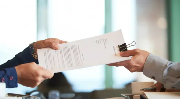 Dwie osoby przekazują sobie dokument "PARTNERSHIP AGREEMENT". To ważny moment, gdy ustalenia stają się faktem.