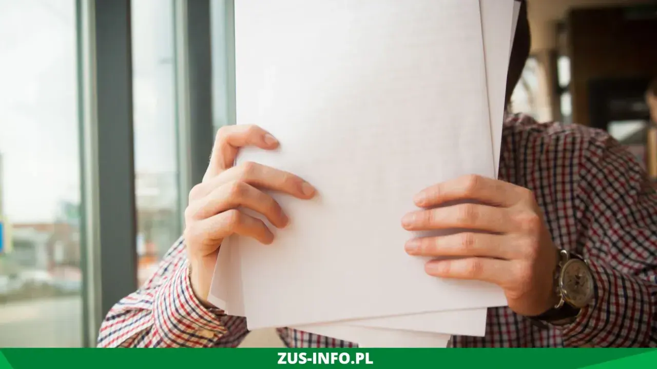 Mężczyzna w kratę trzyma dokumenty, być może wniosek o niezaleganie ZUS.