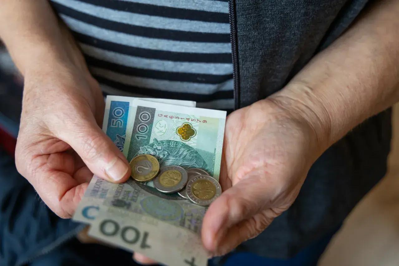Dłonie trzymają banknoty 50 i 100 zł oraz monety. Czy to odzwierciedla średnią emeryturę w Polsce?