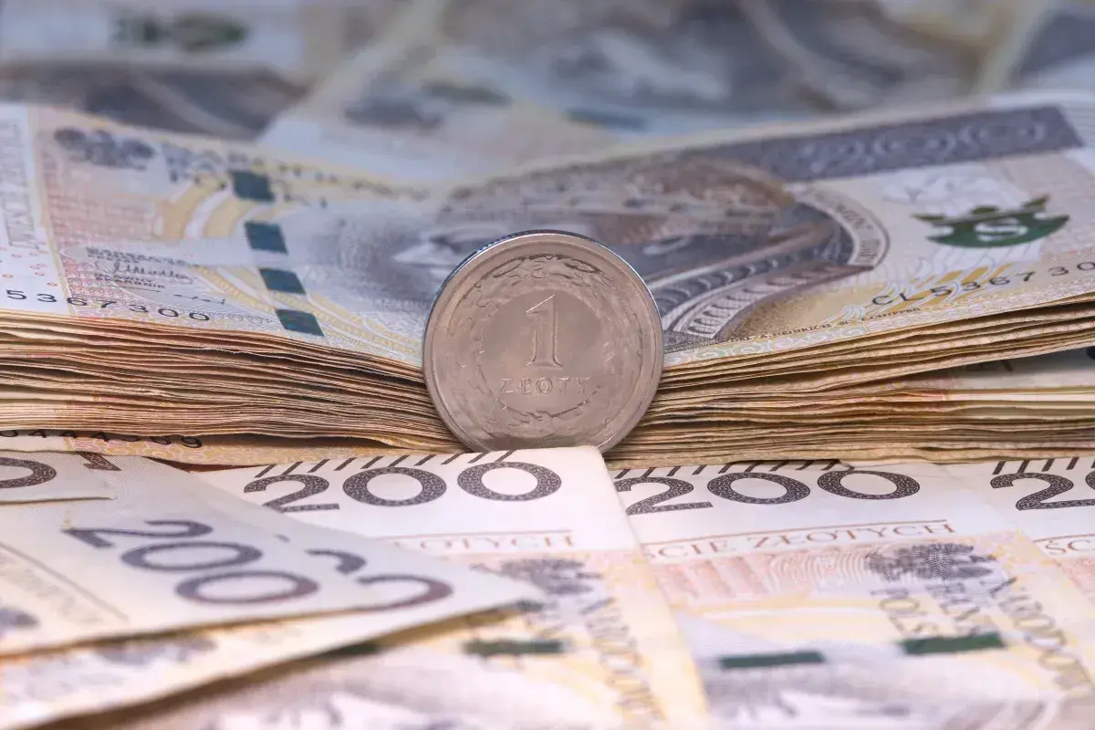 Stos banknotów 200 zł i 100 zł, z monetą 1 zł na wierzchu. Symbolizuje to wynagrodzenie młodocianych, które może być niewielkie na początku kariery.