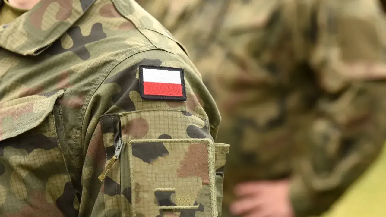 Żołnierz zawodowy w mundurze moro z naszywką z polską flagą.