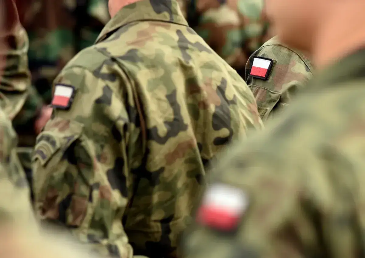 Żołnierz zawodowy w mundurze moro z polską flagą na ramieniu.
