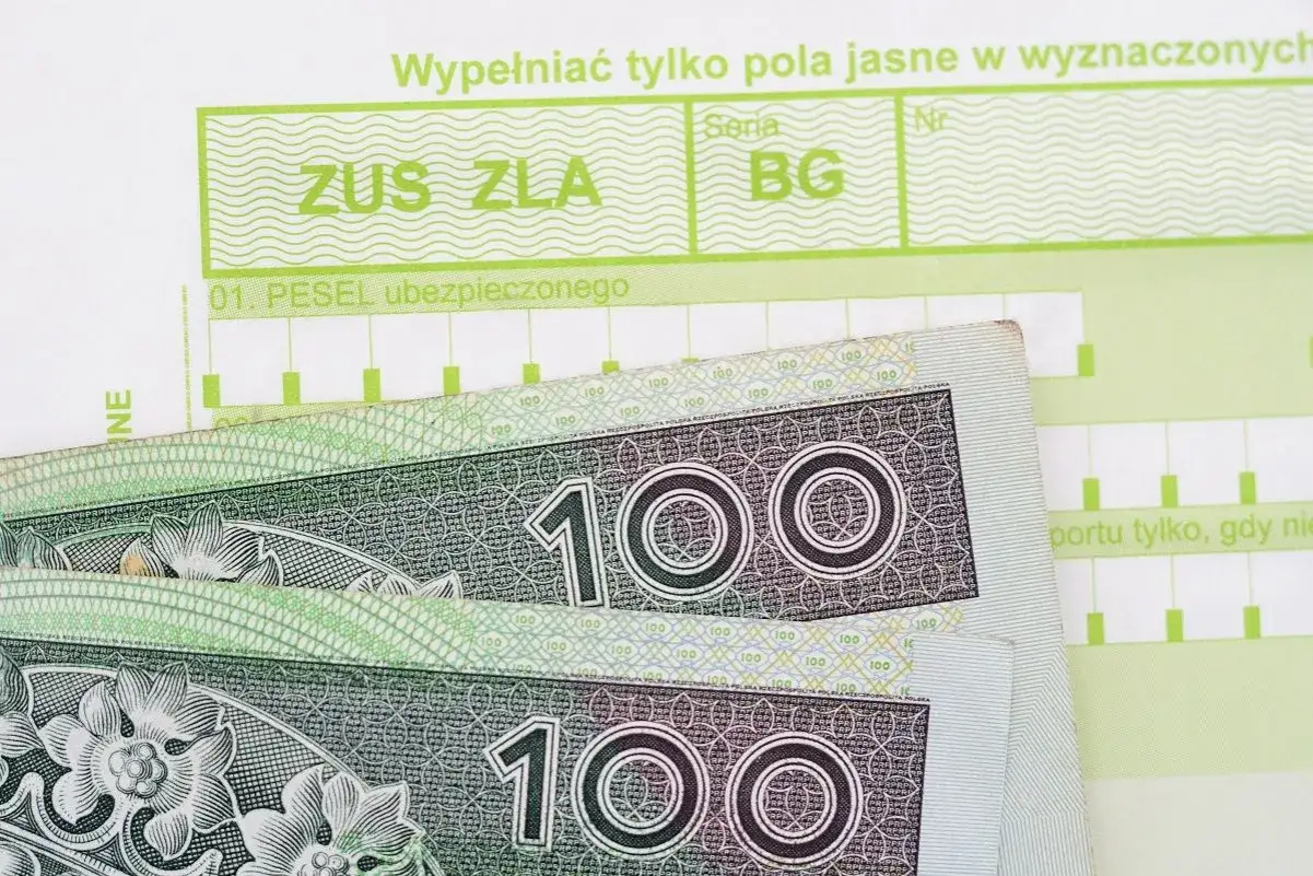 Formularz ZUS ZLA i banknoty 100 zł. Może to oznaczać, że ktoś potrzebuje pieniędzy na zwolnieniu lekarskim.